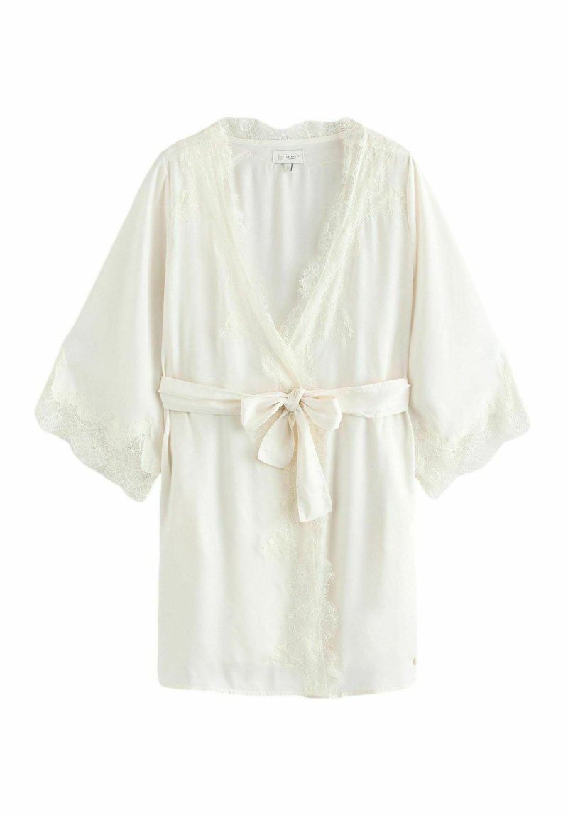 Robe en crème légère avec bord en dentelle, décolleté en V profond et manches larges. Se noue à la taille avec une ceinture en tissu. Texture lisse, design élégant.