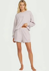 Light lavender loungewear set featuring a loose long-sleeve top with a textured finish and matching shorts with an elastic waistband.