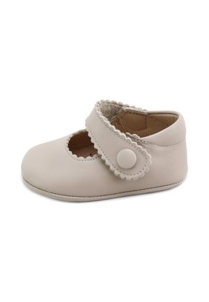 Zapato de bebé suave beige con bordes festoneados, una correa de velcro con un botón redondo y una textura lisa de cuero.