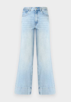 Φαρδιά τζιν παντελόνια σε ανοιχτό γαλάζιο χρώμα με ψηλή μέση, πλεκτές θηλιές ζώνης, μπροστινό κουμπί, φερμουάρ και δύο τσέπες σε λευκό φόντο.