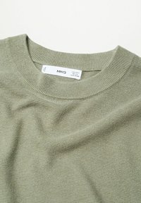 Pull vert clair en maille à col rond avec étiquette de taille et de marque visible indiquant MNG, posé à plat sur une surface blanche.