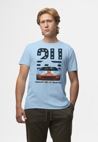 Světle modré bavlněné tričko s grafikou vintage závodního auta, tučný černý text, hvězdy a frází "Circuit de la Sarthe."