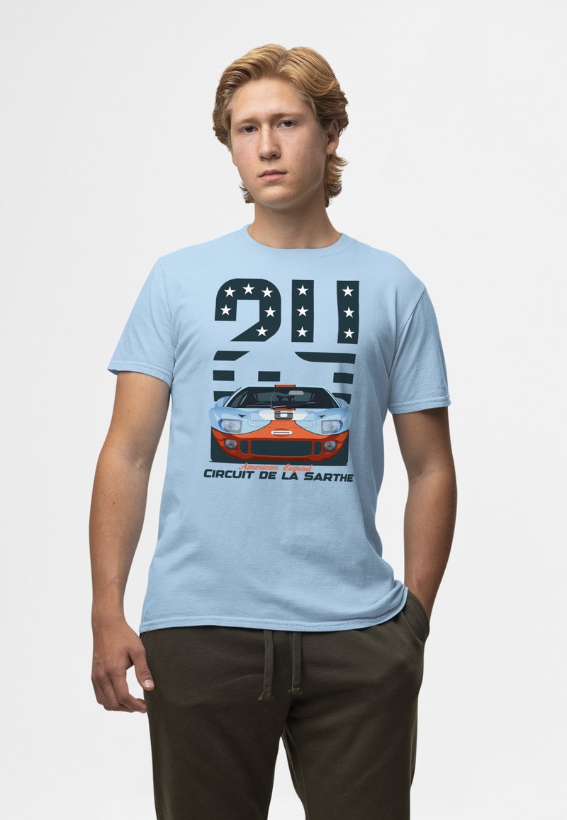 Světle modré bavlněné tričko s grafikou vintage závodního auta, tučný černý text, hvězdy a frází "Circuit de la Sarthe."