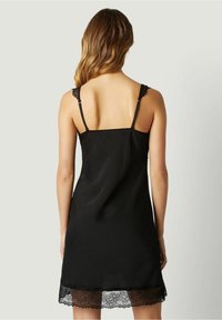 Abito sottoveste in satin nero con bordo in pizzo all'orlo. Presenta spalline sottili e regolabili e una superficie liscia. Design pulito e minimalista.