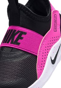 Nahaufnahme eines schwarz-pinken Nike-Sneakers mit elastischem Riemen, "NIKE"-Schriftzug, perforiertem pinkem Seitenpanel und weiß gesprenkelter Sohle mit schwarzem Swoosh.