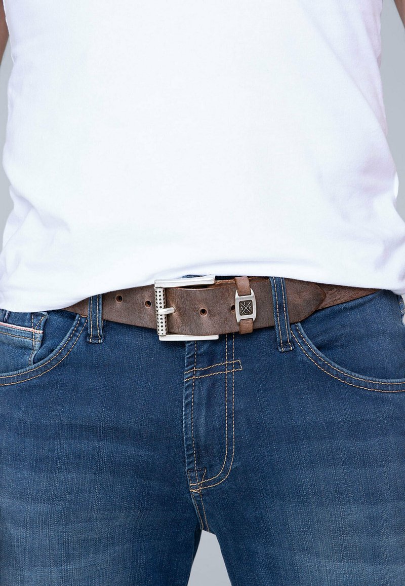 Brown leather belt with silver buckle, featuring a rectangular shape and hole accents, worn over blue denim jeans.