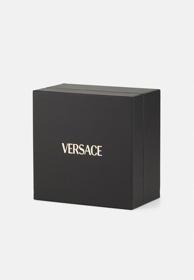 Crni kartonski kutija s mat teksturom, s zlatnim logotipom "VERSACE" na prednjoj strani. Oblik kocke s čistim rubovima.