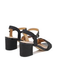 Sandali neri con tacco alto e finitura testurizzata, dotati di cinturini alla caviglia e un tacco quadrato, impreziositi da piccole borchie decorative.