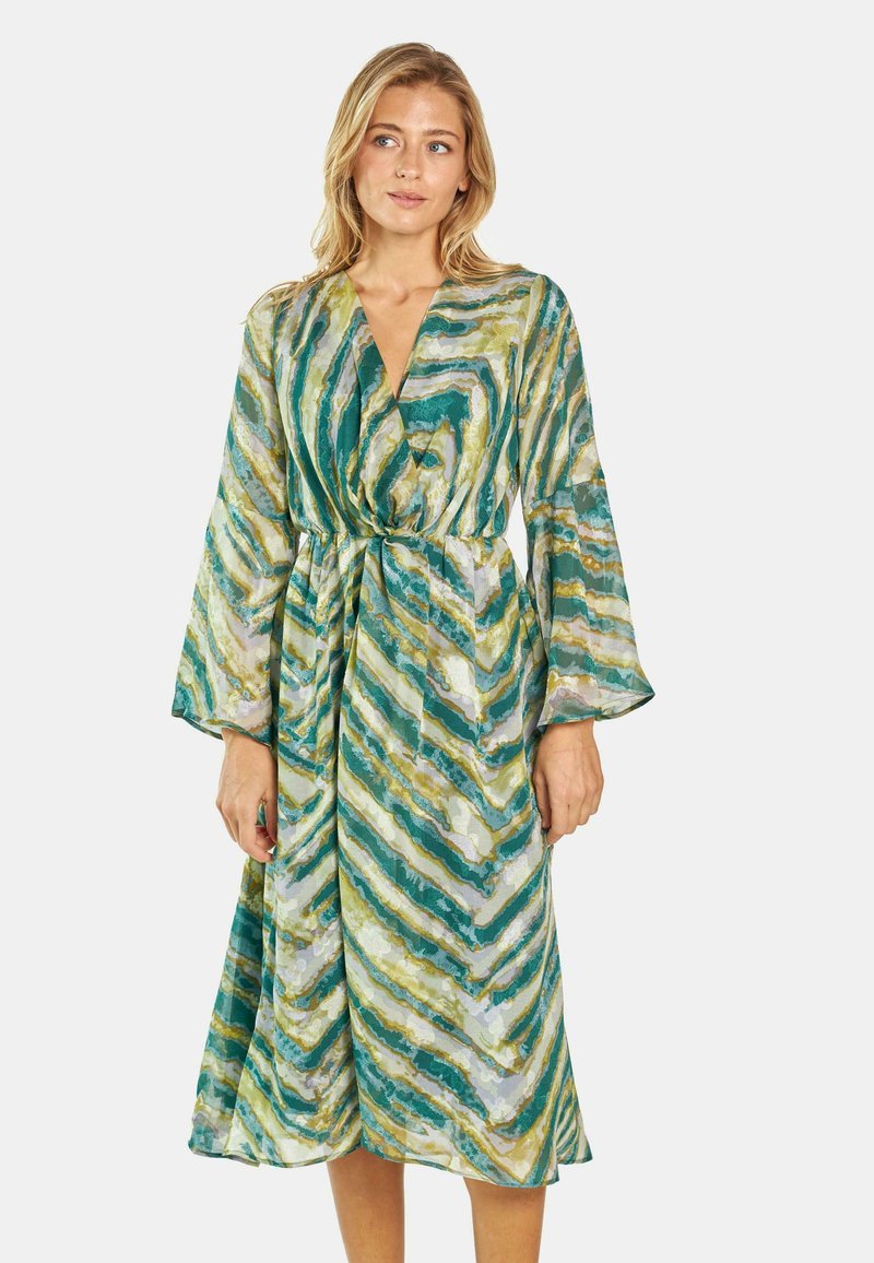Langes Wickelkleid im Chevron-Muster in Grün, Gelb und Weiß. Hergestellt aus leichter Stoffware, mit Glockenärmeln und einer gebundenen Taille.