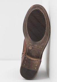 Zapato de cuero marrón con una suela de goma negra texturizada. Entre sus características se incluyen costuras visibles y una marca de talla 37 en la parte inferior.