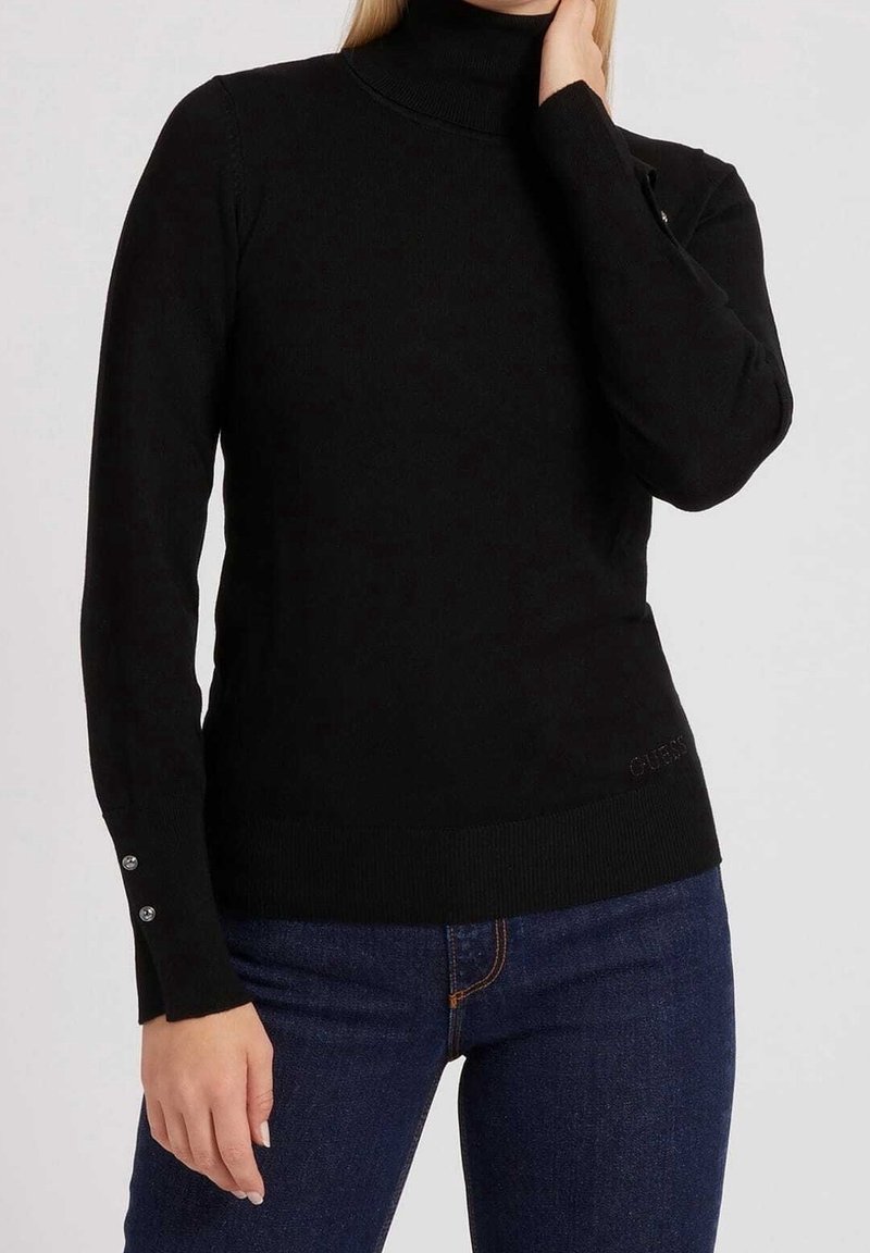 Pull à col roulé noir en tissu doux avec des manches longues, présentant des accents de boutons sur les poignets et un ourlet côtelé. Logo de la marque subtilement affiché.