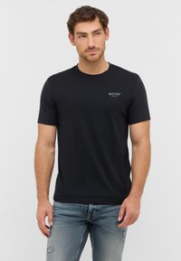Czarny t-shirt z krótkim rękawem wykonany z miękkiej bawełny, z małym białym logo na lewej klatce piersiowej. Prosty, okrągły dekolt.