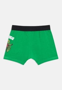 Grüne Jungen-Shorts mit schwarzem Bündchen, ausgestattet mit einer Charaktergrafik auf der linken Seite und aus weichem Baumwollstoff.