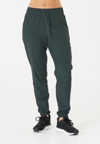 Strechiga, mörkgröna joggers med elastisk midja och justerbar dragkedja. Muddar vid anklarna och mjukt, lätt tyg.