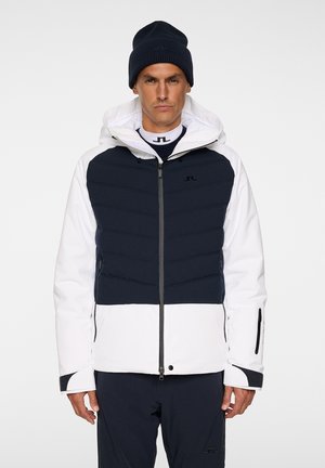 White and navy insulated jacket with a hood, featuring a snug fit, zip closure, and textured upper section; paired with a matching knitted beanie.