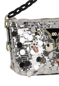 Bolso plateado con lentejuelas y cierre de cremallera, decorado con adornos negros y de colores, con una correa de cadena y forma rectangular.