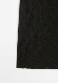 Tissu noir avec un motif diamant texturé et ondulé et des détails froncés et rassemblés créant une surface riche et tactile.