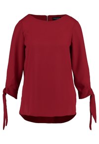 Blusa rossa realizzata in tessuto liscio, con scollo a barca, maniche a tre quarti con lacci e orlo leggermente curvato per un fit rilassato.