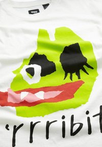 Camiseta de algodón blanca con una gran cara de dibujos animados en verde, ojos negros, boca roja y el texto "'rrribit" en letras negras en negrita.