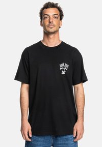 Black cotton t-shirt with short sleeves, featuring a white graphic of crossed checkered flags and a logo on the left chest area.