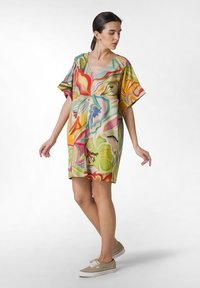 Abito corto, colorato, con maniche corte e scollatura a V, realizzato in tessuto fluido e decorato con motivi floreali astratti nei toni del verde, arancione, rosa e giallo.