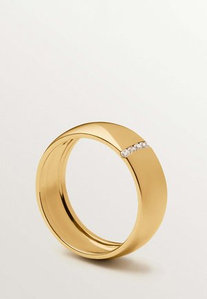 Anillo de banda dorada con un acabado liso que presenta una fila horizontal de pequeñas piedras preciosas transparentes incrustadas en un lado.