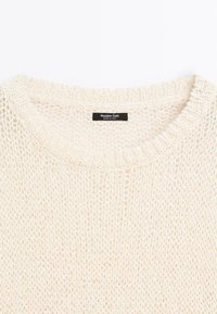 Sweter z luźnym splotem w kremowym kolorze, z okrągłym dekoltem. Posiada fakturowany materiał oraz metkę z napisem "Massimo Dutti, wyprodukowano we Włoszech."