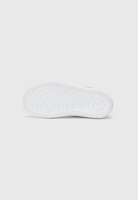 Semelle de sneaker blanche avec un motif de grip texturé, des détails circulaires et linéaires, et un rebord surélevé. Design minimaliste sans marquage visible.