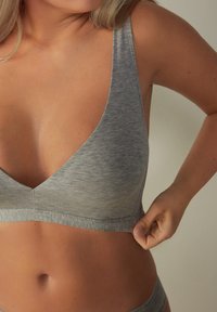 Grijze stoffen bralette met een V-halsontwerp, brede bandjes en een naadloze band. Zachte, rekbare textuur die geschikt is voor comfort en aanpassing van de pasvorm.