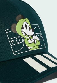 Gorra verde con un gráfico de un personaje en una sudadera verde. Presenta tres rayas blancas en la visera y un diseño estructurado.