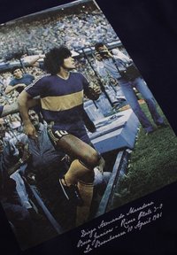 Grafische t-shirt met een vintage foto van een mannelijke atleet in een blauw en geel shirt, omringd door fans in een stadionomgeving.