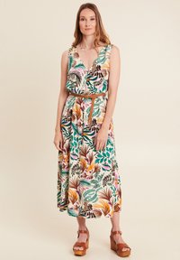 Kleid mit Floralprint, V-Ausschnitt, ärmellosem Design, tailliertem Schnitt mit geflochtenem Gürtel und mehrfarbigen tropischen Blättern auf hellem Hintergrund.