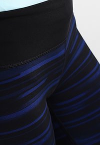 Blå och svarta träningsleggings med horisontella ränder, tillverkade av elastiskt material, med hög midja och platta sömmar.