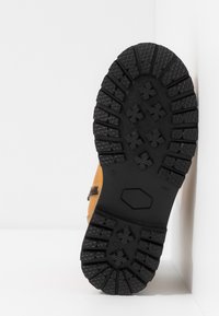 Stivale marrone in pelle con suola in gomma nera testurizzata. La suola presenta profonde scanalature per una maggiore aderenza e durata.