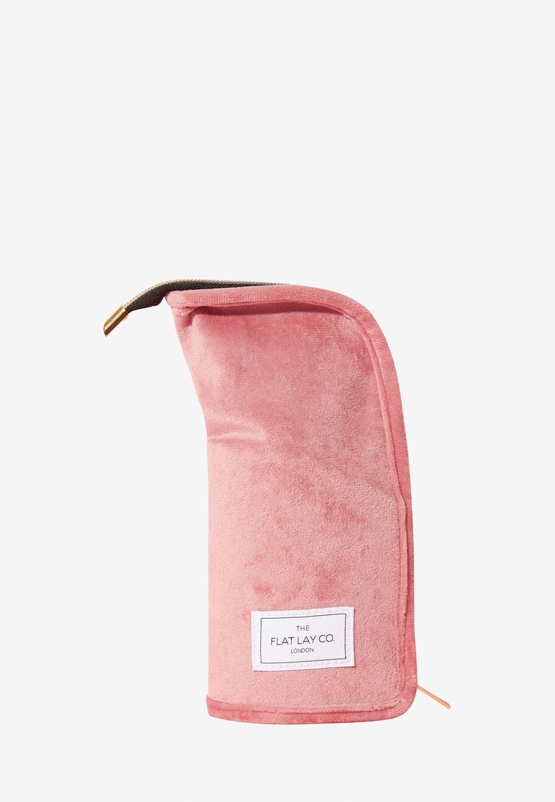 Myk rosa rektangulær toalettmappe med glidelås og en hvit etikett med påskriften "The Flat Lay Co. London" på den ene siden.