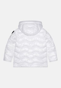 Bela puhovka s kapuco, z odebeljenim teksturo in valovitim vzorcem. Vključuje črn poudarek na rokavu.