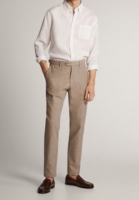 Lichtgewicht wit linnen overhemd met knoopsluiting; beige op maat gemaakte broek; bruine leren loafers. Eenvoudig ontwerp met een zakdetail.