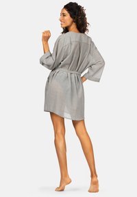 Szary szlafrok z paskiem, luźny krój, szerokie rękawy i teksturowany materiał. Posiada boczne kieszenie i sięga do połowy uda. Lekki i przewiewny design.