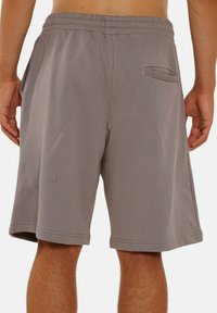 Gray athletic shorts made of soft, stretchy fabric. Features an elastic waistband and welt pocket on the right side. Mid-thigh length.