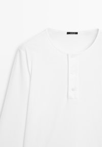 Weißes Langarmshirt mit rundem Halsausschnitt und drei weißen Knöpfen an der vorderen Blende, schlichtes Design, keine sichtbaren Muster oder Logos.