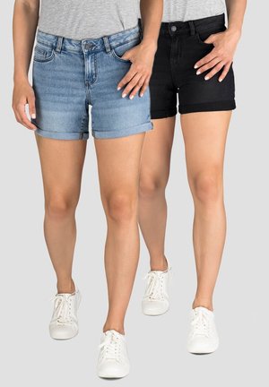 Denim shorts in lichtblauw en zwart, opgerolde uiteinden, klassieke pasvorm, vijf-pocket ontwerp, gecombineerd met witte sneakers op een grijze achtergrond.