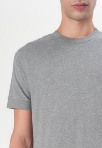 Grijze katoenen t-shirt met een ronde hals en korte mouwen. Zachte textuur met een gladde afwerking. Minimalistisch ontwerp, geen patronen of accenten.