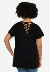 Czarny t-shirt z krótkim rękawem z laced-up designem z tyłu. Miękka tkanina, luźny krój i okrągły dekolt. Brak widocznych wzorów lub elementów metalowych.