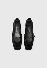 Les ballerines noires à bout carré possèdent un dessus texturé agrémenté de petits clous et d'un accent de nœud central. L'intérieur en cuir doux offre un confort optimal.