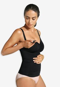 Svart graviditetstopp med justerbara band, rynkdetalj vid bysten, kombinerad med ljusrosa trosor, slät tygtextur.