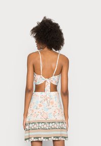 Conjunto de duas peças floral, com um top estampado com flores, alças e atilho nas costas, combinado com uma saia correspondente e uma banda decorativa na bainha.
