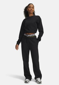 Sweatshirt noir avec un col rond et un logo en relief ; pantalon de jogging noir assorti avec une taille élastique dotée d'une ceinture de marque contrastante.