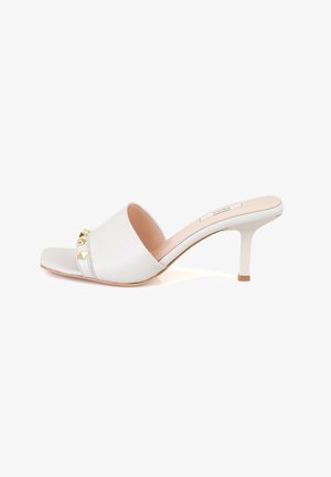 White leather slip-on sandal with a square toe, a low heel, and gold pyramid studs across the front. Smooth texture with minimal stitching.