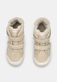 Beżowe sneakersy za kostkę z puszystą podszewką, dwoma paskami na rzep, gumowymi podeszwami i naszywką z logo na pięcie. Gładka, skórzana faktura.