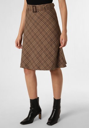 Jupe patineuse marron à carreaux avec ceinture assortie, portée avec des bottines noires et un haut noir, montrée de la mi-cuisse vers le bas.